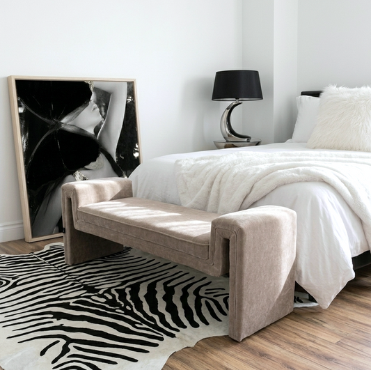 Solace textured bench in natural taupe, waterfall silhouette with upholstered arms styled at the end of a bed on a zebra print rug