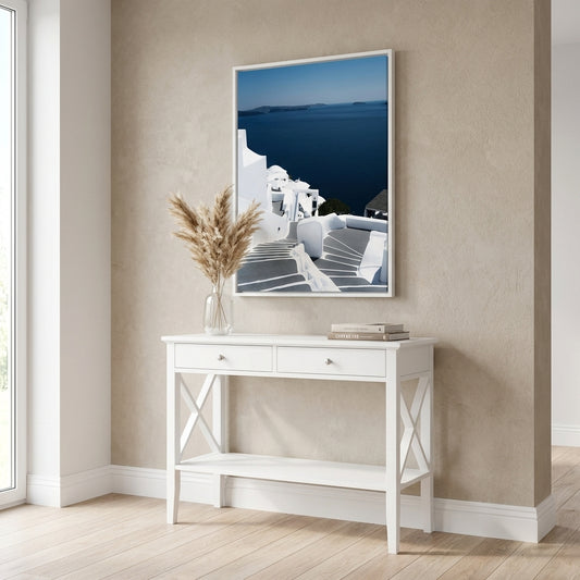 White console table with decorative items against a beige wall with a framed picture.
