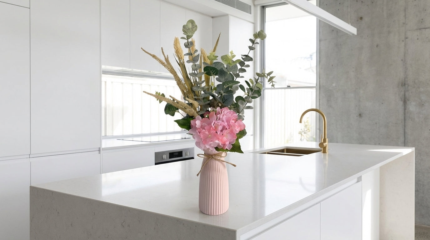 Pink vase with flowers on a kitchen counter