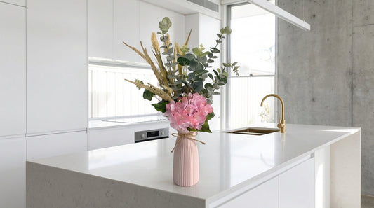 Pink vase with flowers on a kitchen counter