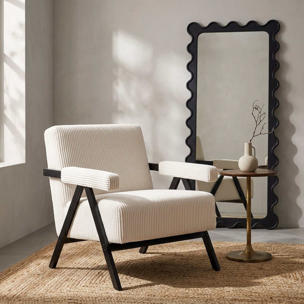 Aster white corduroy armchair beside a wavy black mirror and round side table in a warm neutral room