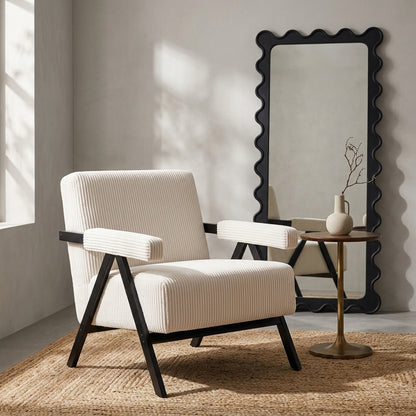 Aster white corduroy armchair beside a wavy black mirror and round side table in a warm neutral room
