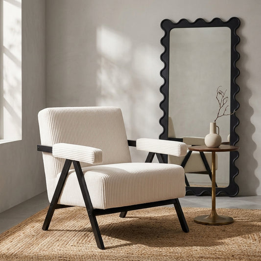 Aster white corduroy armchair beside a wavy black mirror and round side table in a warm neutral room