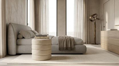 Cleo nude boucle ottoman in a bedroom with dark linen and floor-to-ceiling window