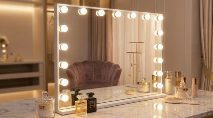 Makeup vanity with a mirror with lights and various beauty products on a marble surface.
