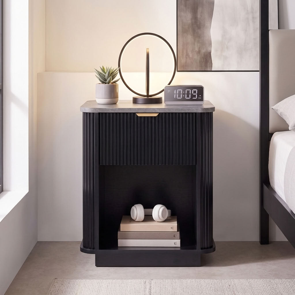 Tura black fluted bedside table with marble-effect top, styled with a round LED lamp, succulent, alarm clock and headphones in a contemporary bedroom