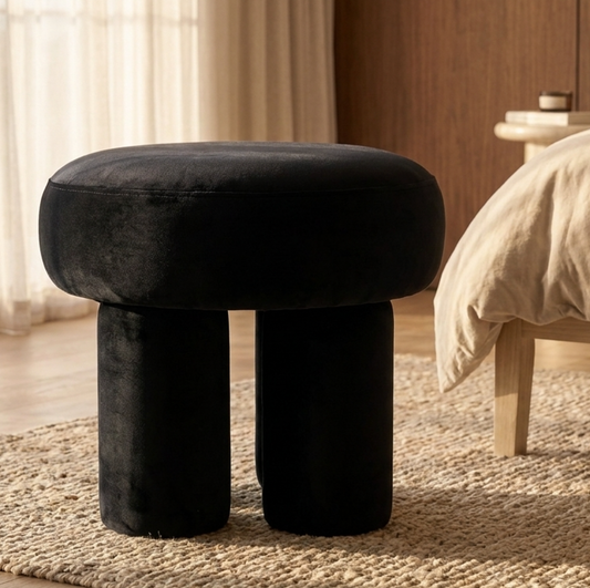 Interior Ave Black cushioned stool in a room with a bed and curtains