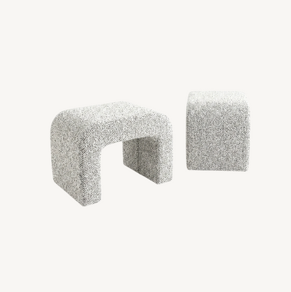 Hendrix arched textured ottoman in frosted stone boucle, sculptural arch cut-out form styled at the end of a bed in a neutral bedroom