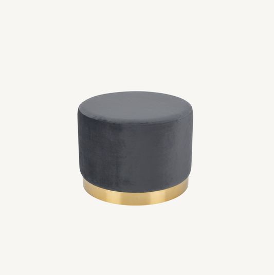 Monaco round ottoman in ocean grey-blue velvet with brushed gold base, styled beside a round gold glass coffee table on a jute rug