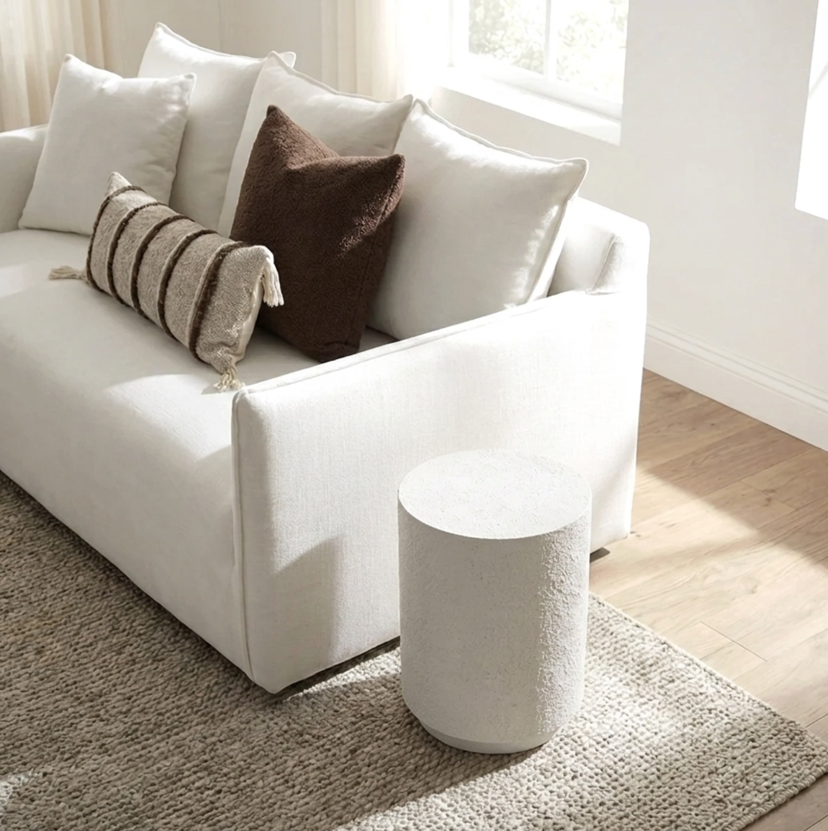 Muse fossil side table styled beside a cream sofa with warm neutral cushions and a soft textured rug