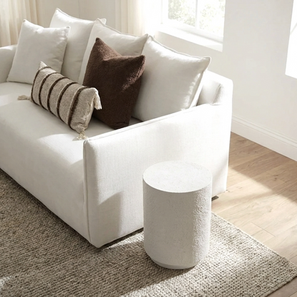 Muse fossil side table styled beside a cream sofa with warm neutral cushions and a soft textured rug