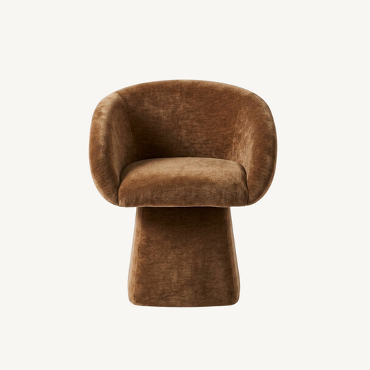 Merlo swivel chair in cinnamon, sculptural curved form with ribbed upholstery and pedestal base styled in a warm bedroom setting