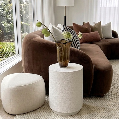 Muse fossil side table close-up beside a brown leather sofa with a decorative vase on top
